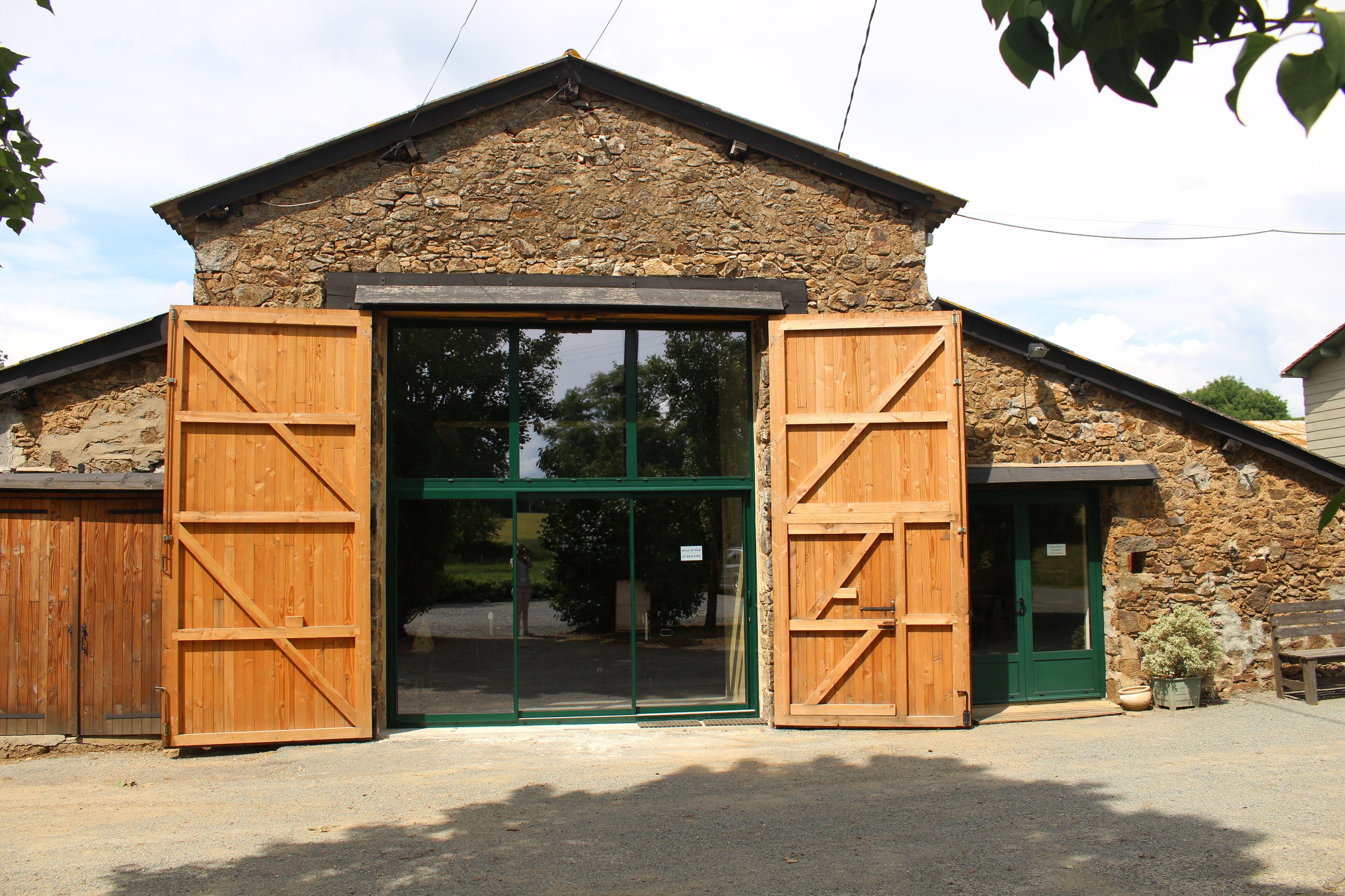 A rustic stone building with a large wooden door and a green door.