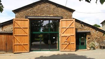 A rustic stone building with a large wooden door and a green door.