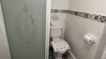 Een badkamer met toilet, douche en vloertegels met een patroon.