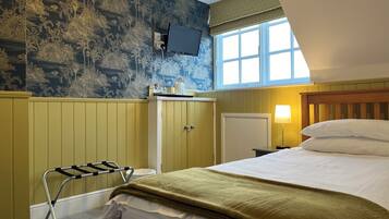A hotel room with a bed, a TV mounted on the wall, a window with a view, and a wooden cabinet.