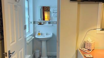 A bathroom with a white sink, a mirror, a towel rack, and a television mounted on the wall.