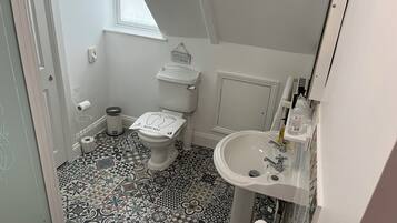 A bathroom with a toilet, sink, and patterned floor tiles.
