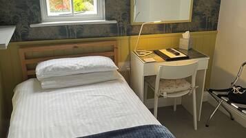 A bedroom with a bed, a desk, a chair, a window, and a mirror.