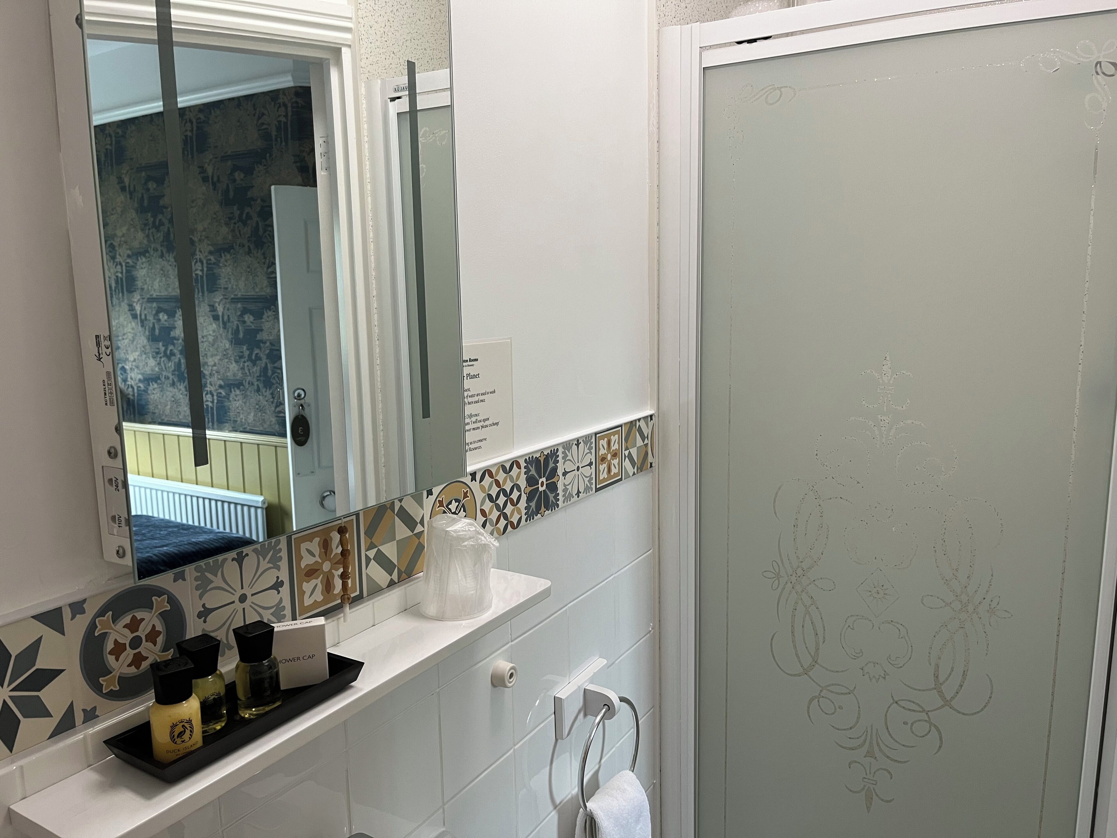 A bathroom with a white sink, a mirror, a shower door, and a towel rack.