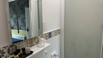 A bathroom with a white sink, a mirror, a shower door, and a towel rack.