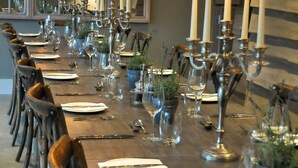 A long dining table set with candles, plates, cutlery, and glasses, surrounded by chairs. - The Red Lion Inn (Somerton)