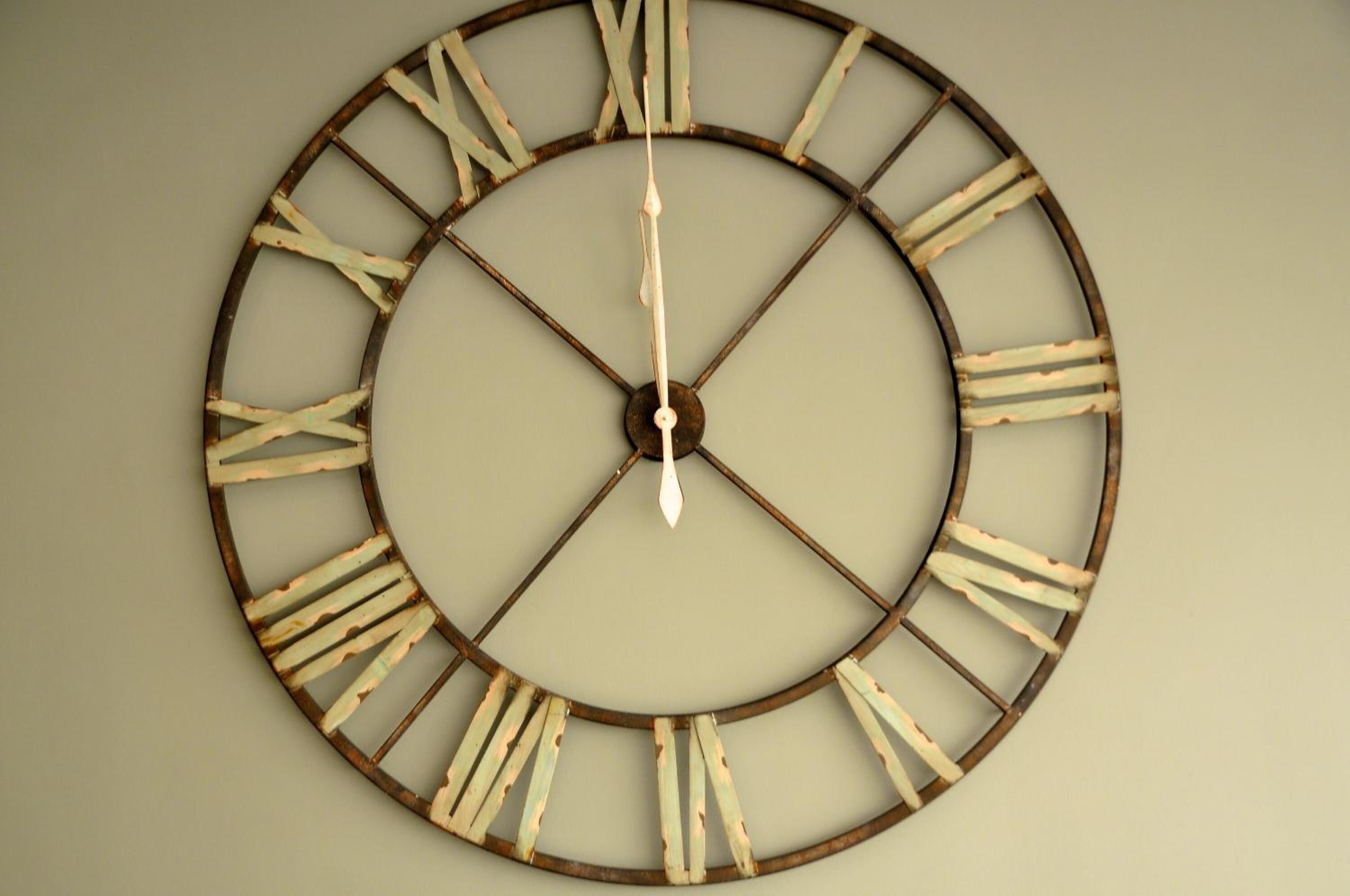 Un reloj de pared grande y circular con números romanos y un diseño minimalista.