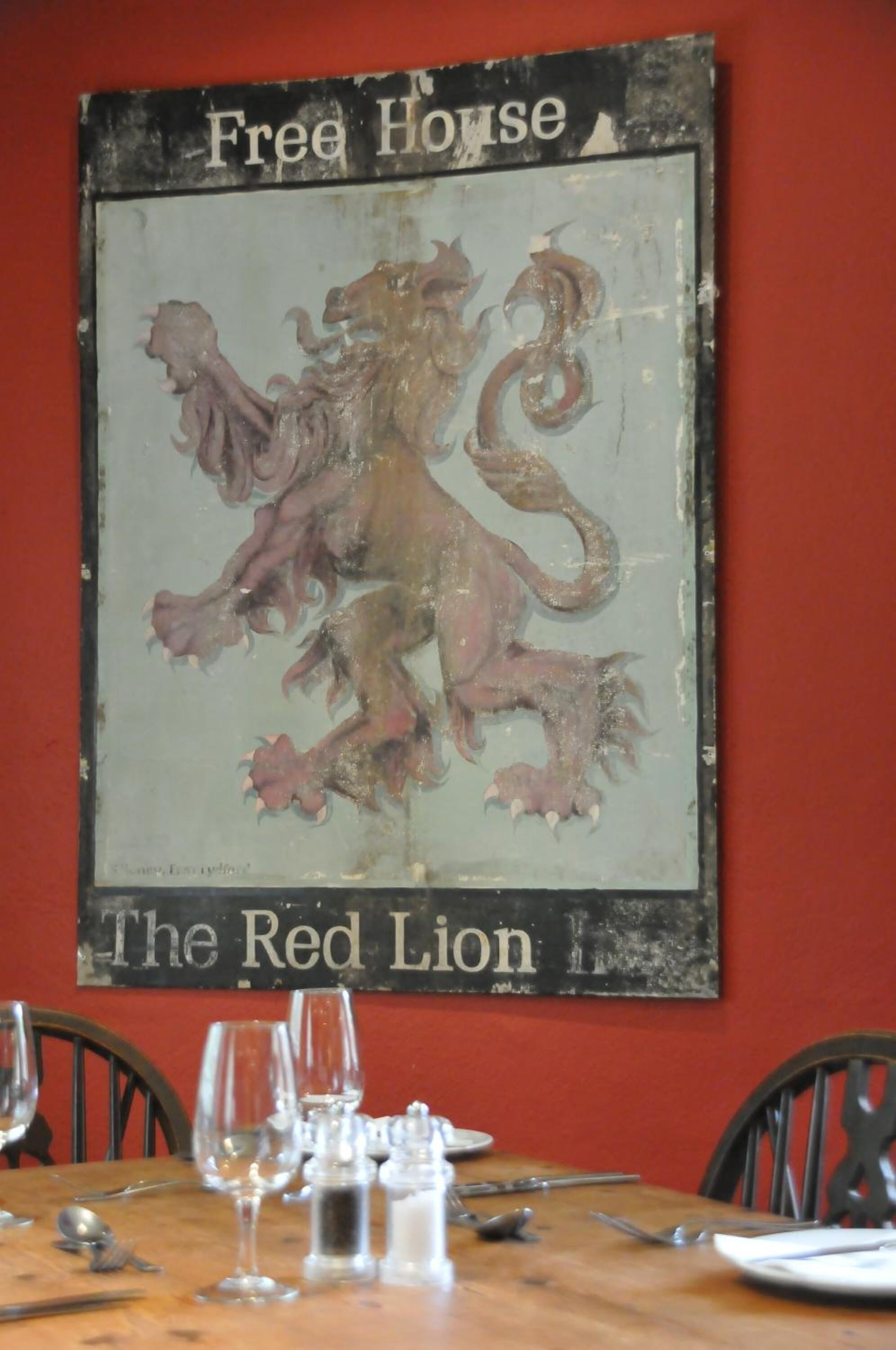 A framed emblem of a red lion with the text "Free House" and "The Red Lion" on a wall.