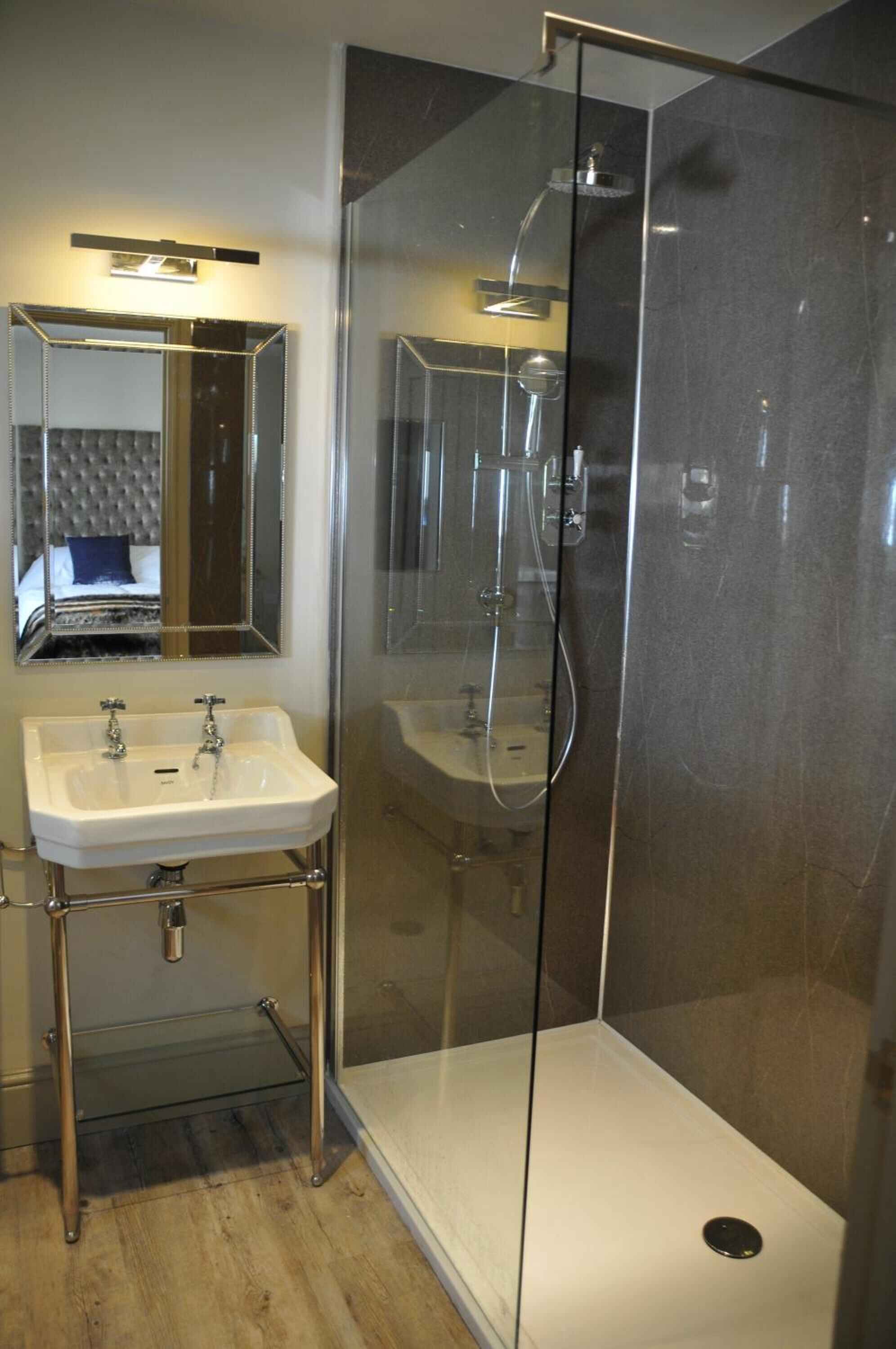 Une salle de bain moderne avec une douche à parois de verre, un lavabo blanc et un miroir au-dessus du lavabo.
