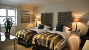 A hotel room with two beds, a large window, a potted plant, and a painting on the wall. - The Red Lion Inn (Somerton)
