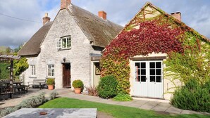 A stone house with a thatched roof and ivy-covered walls. - The Red Lion Inn (Somerton)