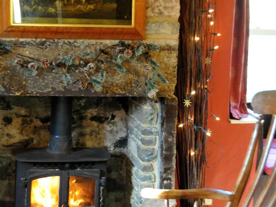 A rustic interior with a stone fireplace, a wooden chair, and a painting on the wall.