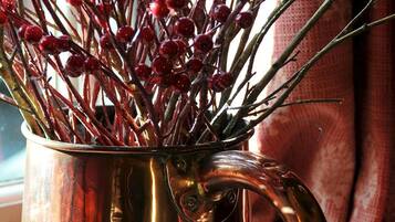 A copper mug filled with red berries and branches.