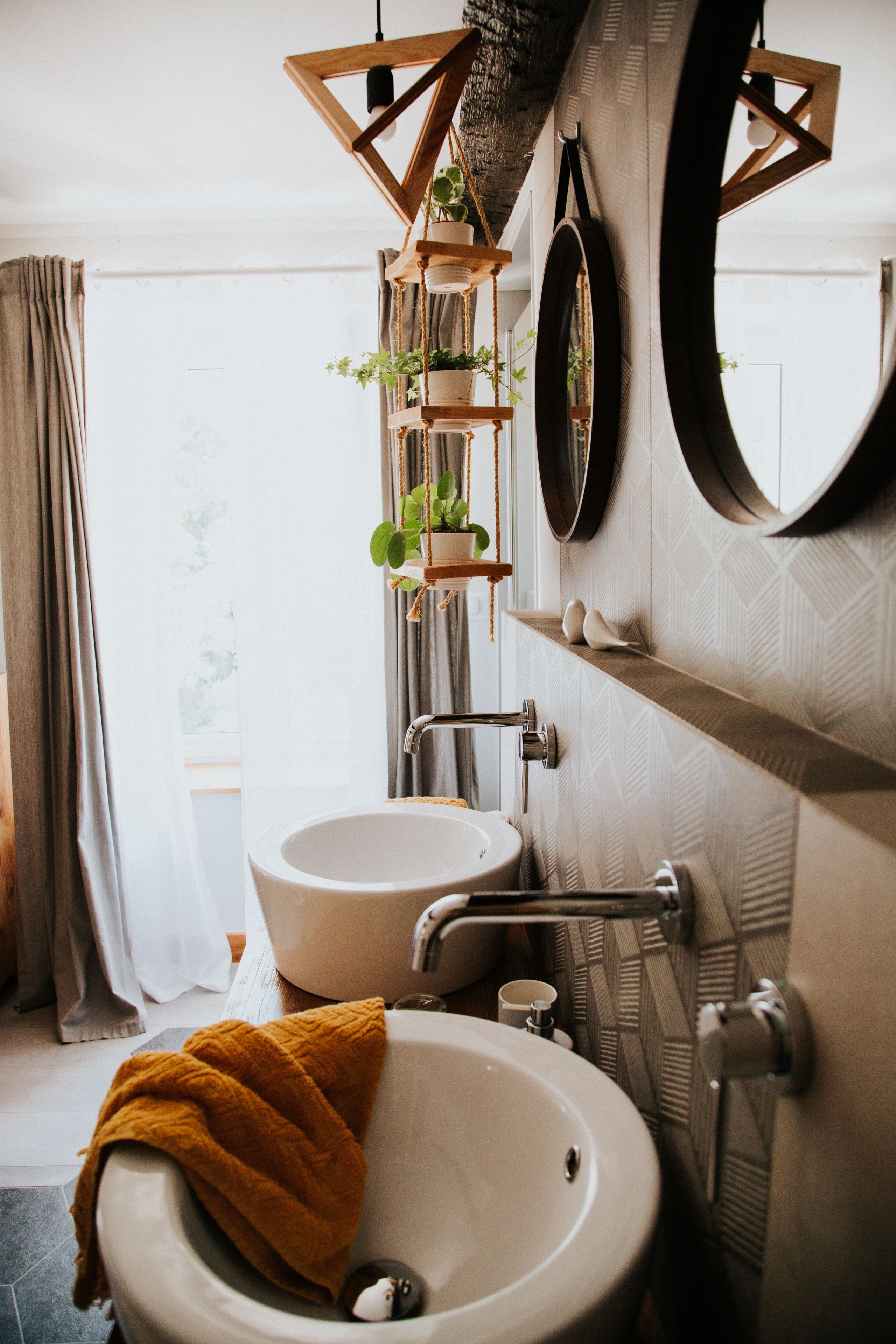 Ein Badezimmer mit einem weißen Waschbecken, einem Spiegel und einem Holzboden mit Pflanzen.