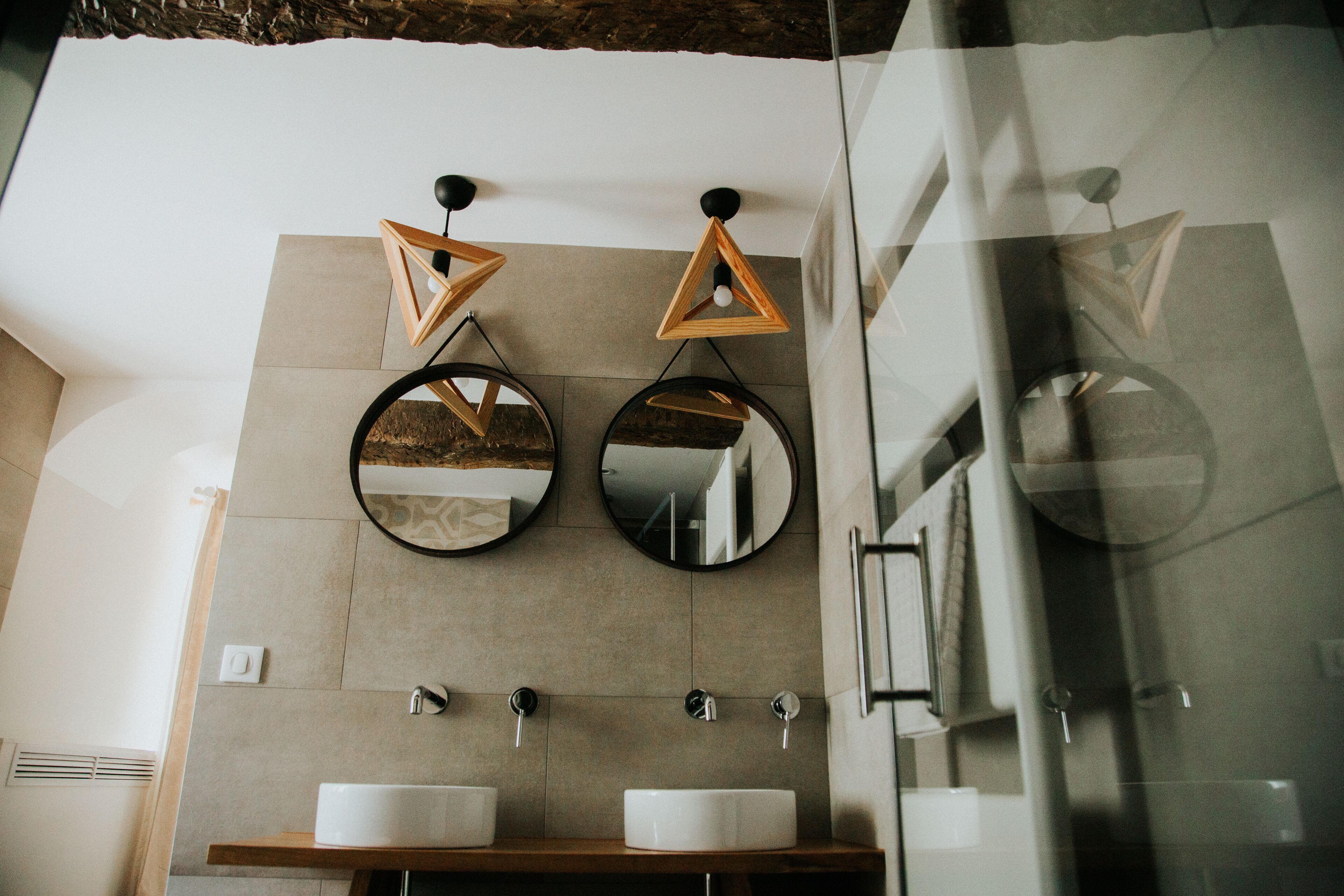 A bathroom with two sinks, two mirrors, and a wooden vanity.