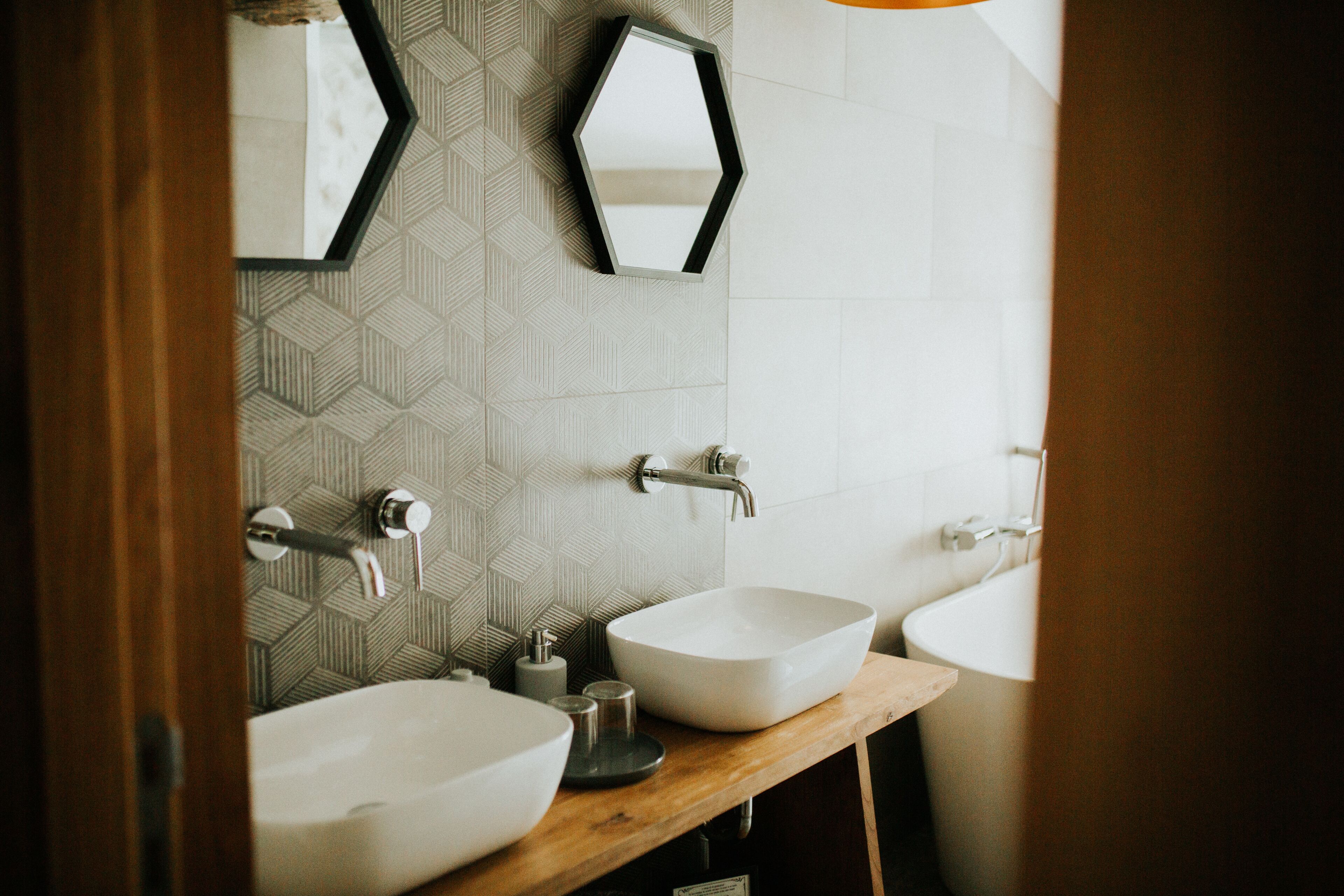 A bathroom with two sinks, a mirror, and a geometric patterned wall.