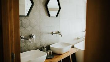 A bathroom with two sinks, a mirror, and a geometric patterned wall.