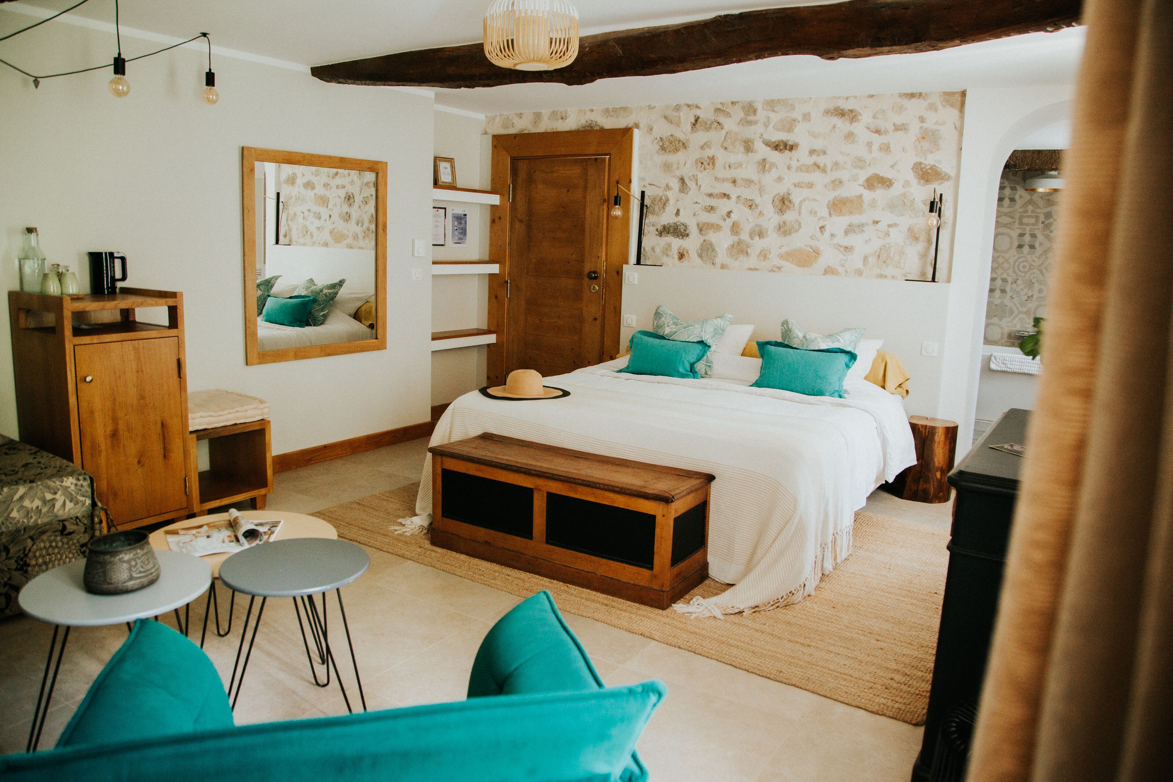 A cozy bedroom with a bed, a wooden bench, a small table, and a mirror.
