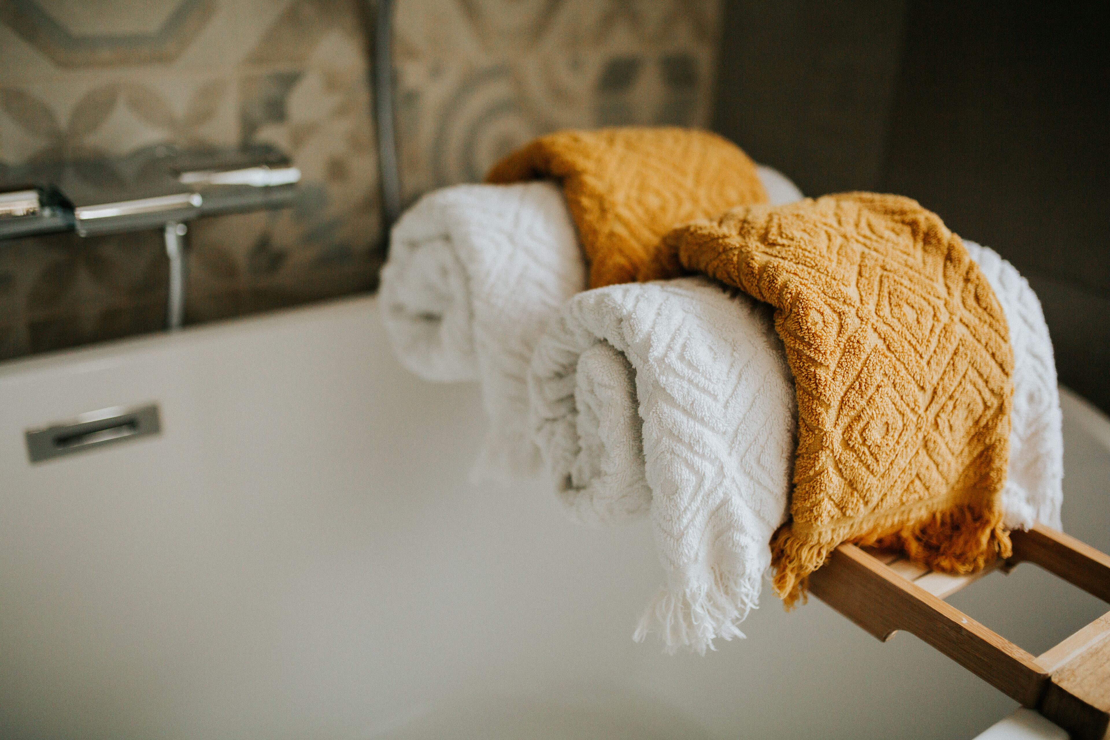 Un baño con bañera, toallero y pared estampada.