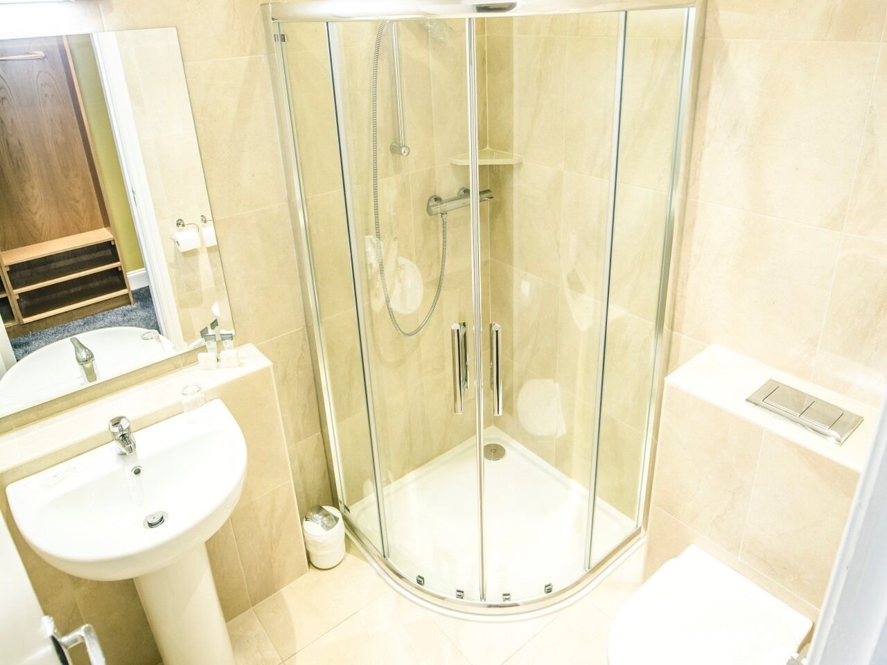 A modern bathroom with a glass-enclosed shower, a sink, and a toilet.