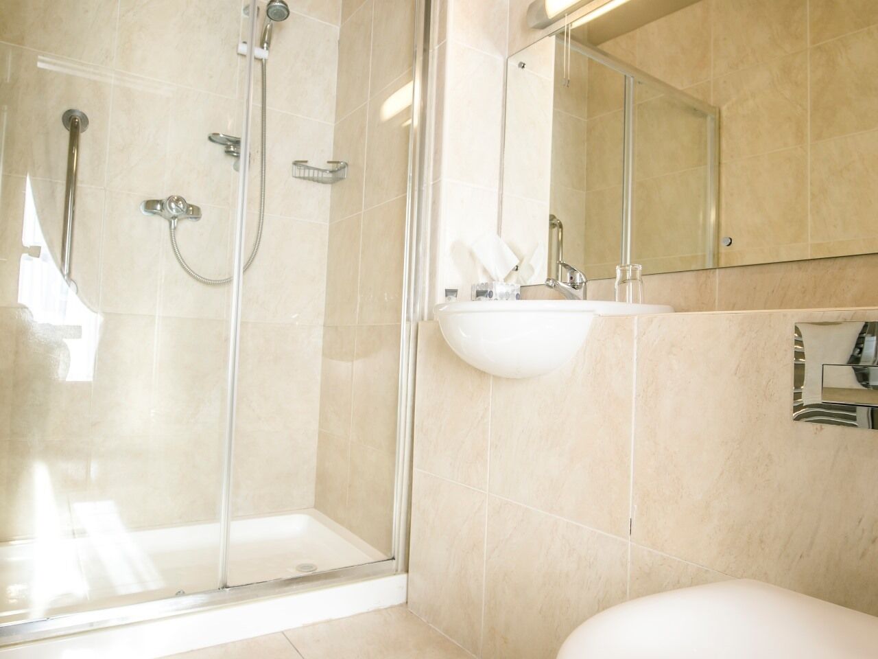 A modern bathroom with a glass-enclosed shower, a white sink, and a large mirror.