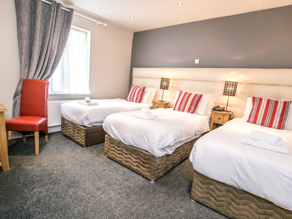 Une chambre d’hôtel avec deux lits, une chaise rouge et une petite table.