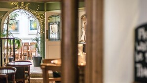 Vista del interior de un restaurante con mobiliario de madera, una alfombra roja y un arco decorativo con luces.
