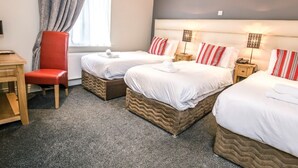 Habitación de hotel con dos camas, una silla roja, un escritorio y una ventana con cortinas.