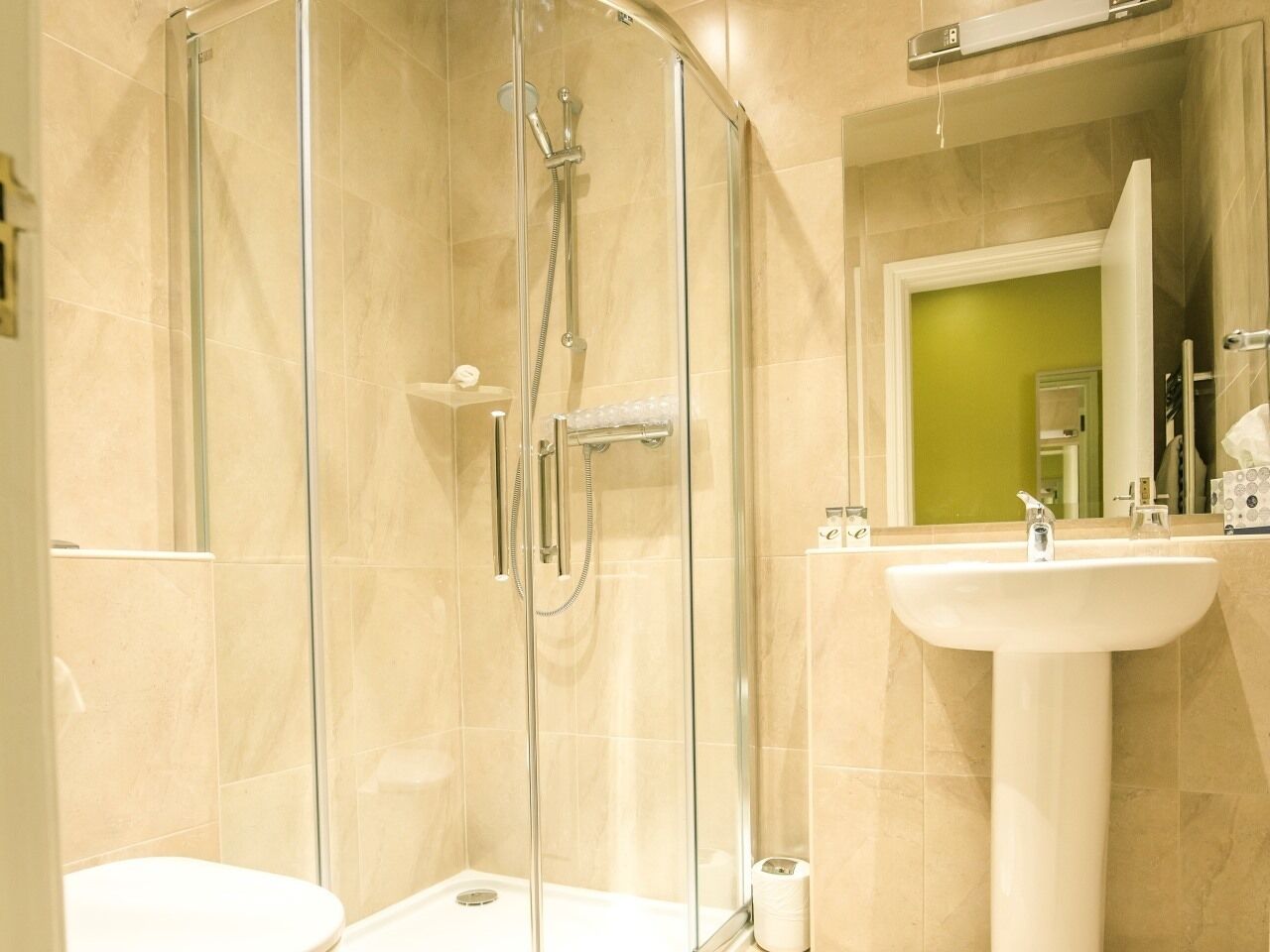A modern bathroom with a glass-enclosed shower, a white sink, and a toilet.
