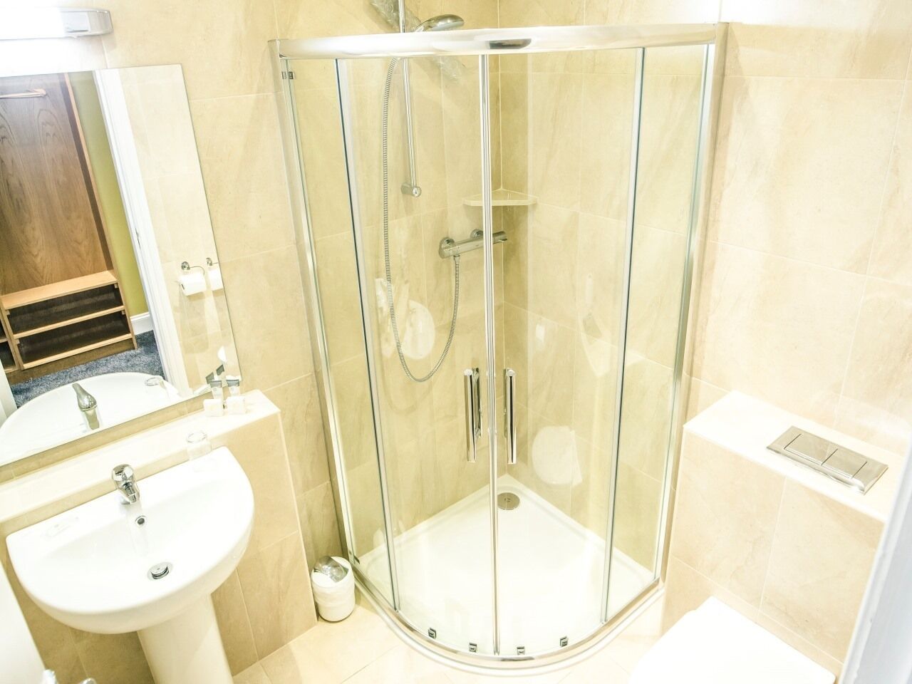 Een moderne badkamer met een douchecabine van glas, een wastafel en een spiegel.
