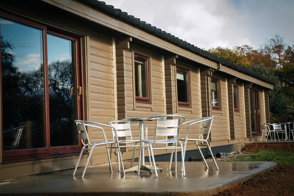 A building with large windows and a patio area with metal chairs.