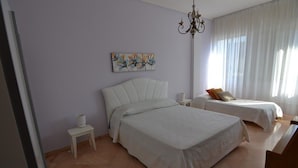A bedroom with two beds, a chandelier, a painting on the wall, and a small table. - B&B Domus Lupiae (Lecce)