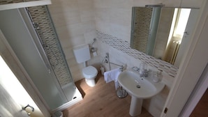 A bathroom with a glass shower enclosure, a toilet, a sink, and a mirror. - B&B Domus Lupiae (Lecce)