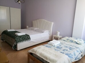 Un dormitorio con una cama individual, una cama más pequeña, una mesita de noche y un armario.