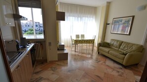A compact living space with a kitchen, dining area, and a sofa. - B&B Domus Lupiae (Lecce)