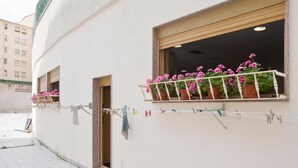 A building with a balcony with potted plants and a clothesline with clothes. - Albergue Albas - Hostel (Logroño)