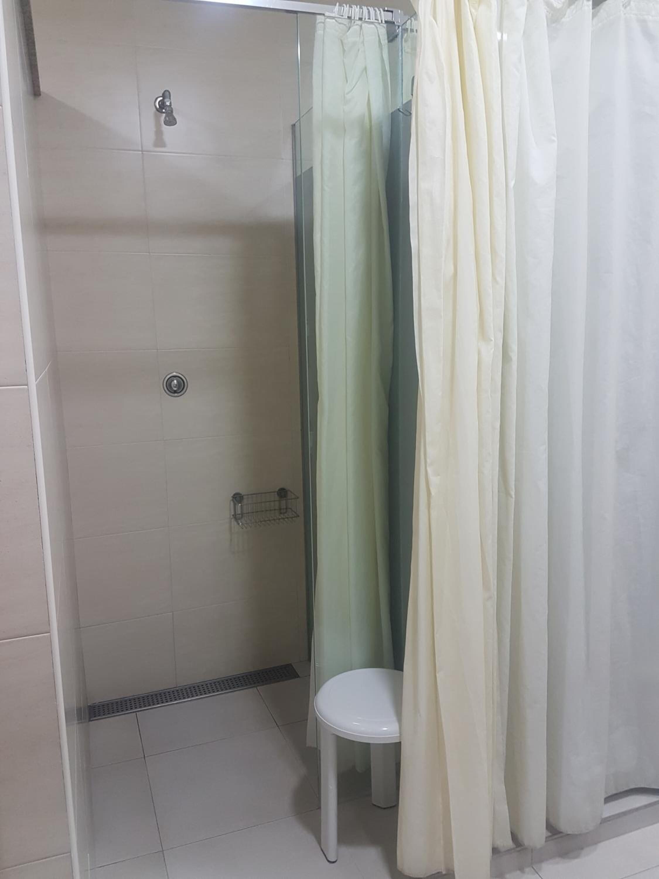 A shower area with a glass door, a white toilet, and a shower curtain.