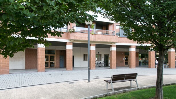 A building with a brick facade, a balcony, and a bench in front. - Albergue Albas - Hostel (Logroño)