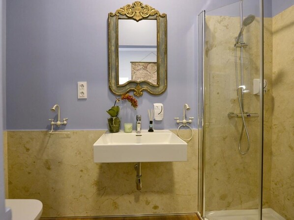 Un baño con lavamanos blanco, un espejo, ducha y retrete.