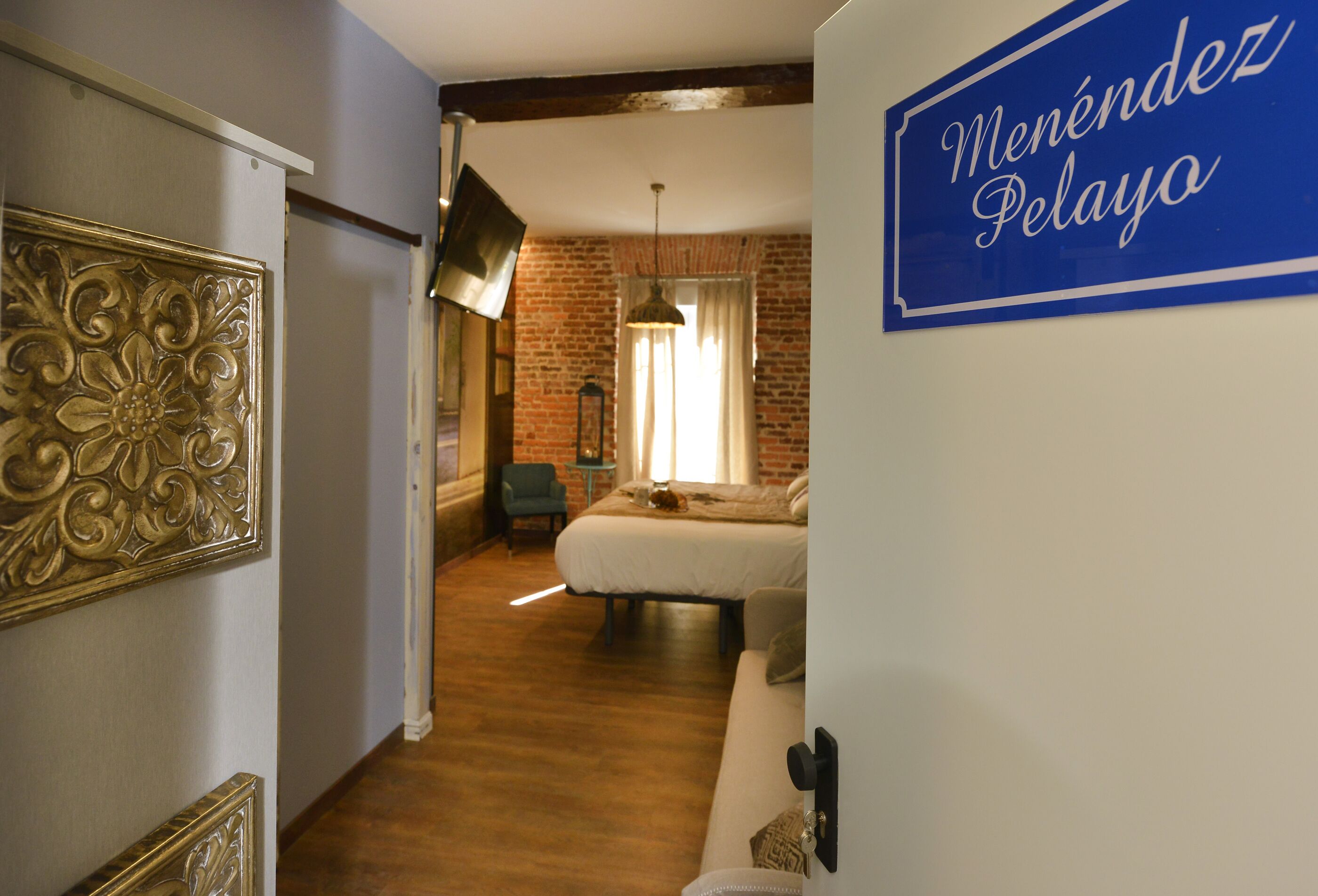 A hotel room with a bed, a chair, a table, and a decorative wall panel.
