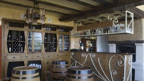 A bar area with wooden barrels, a bar counter, and a wine rack with bottles. - Hotel con encanto - SPA Kinédomus Bienestar (Fresnillo de las Dueñas)
