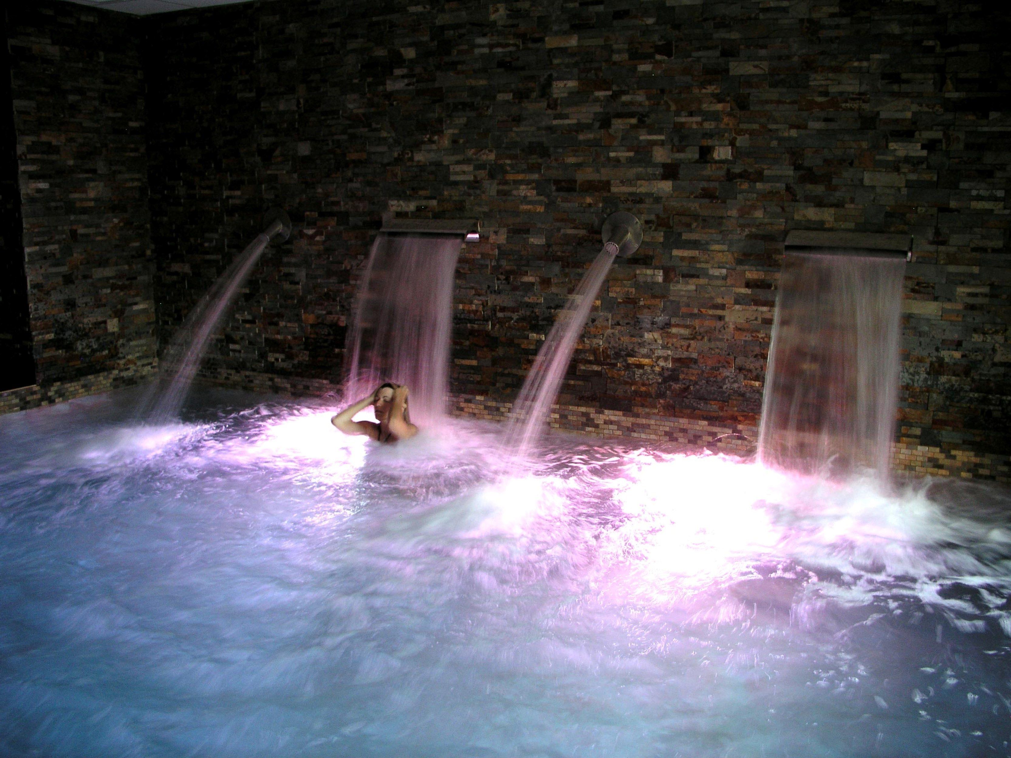 Zona de spa con pared de ladrillo y tres cascadas.