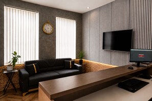 Ein modernes Wohnzimmer mit einer Couch, einem Holztisch, einem Fernseher und einer Wanduhr.
