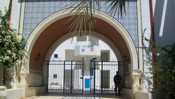 An entrance with a large arched doorway, a gated entrance, and steps leading up to the door. - El Goulli Appartement (Hergla)
