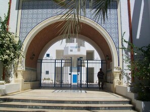 An entrance with a large arched doorway, a gated entrance, and steps leading up to the door. - El Goulli Appartement (Hergla)
