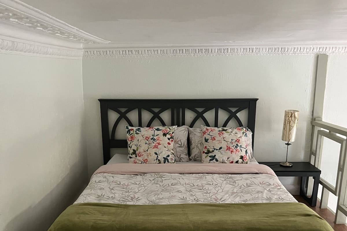 A bed with a floral bedspread, a green throw blanket, and a dark headboard.
