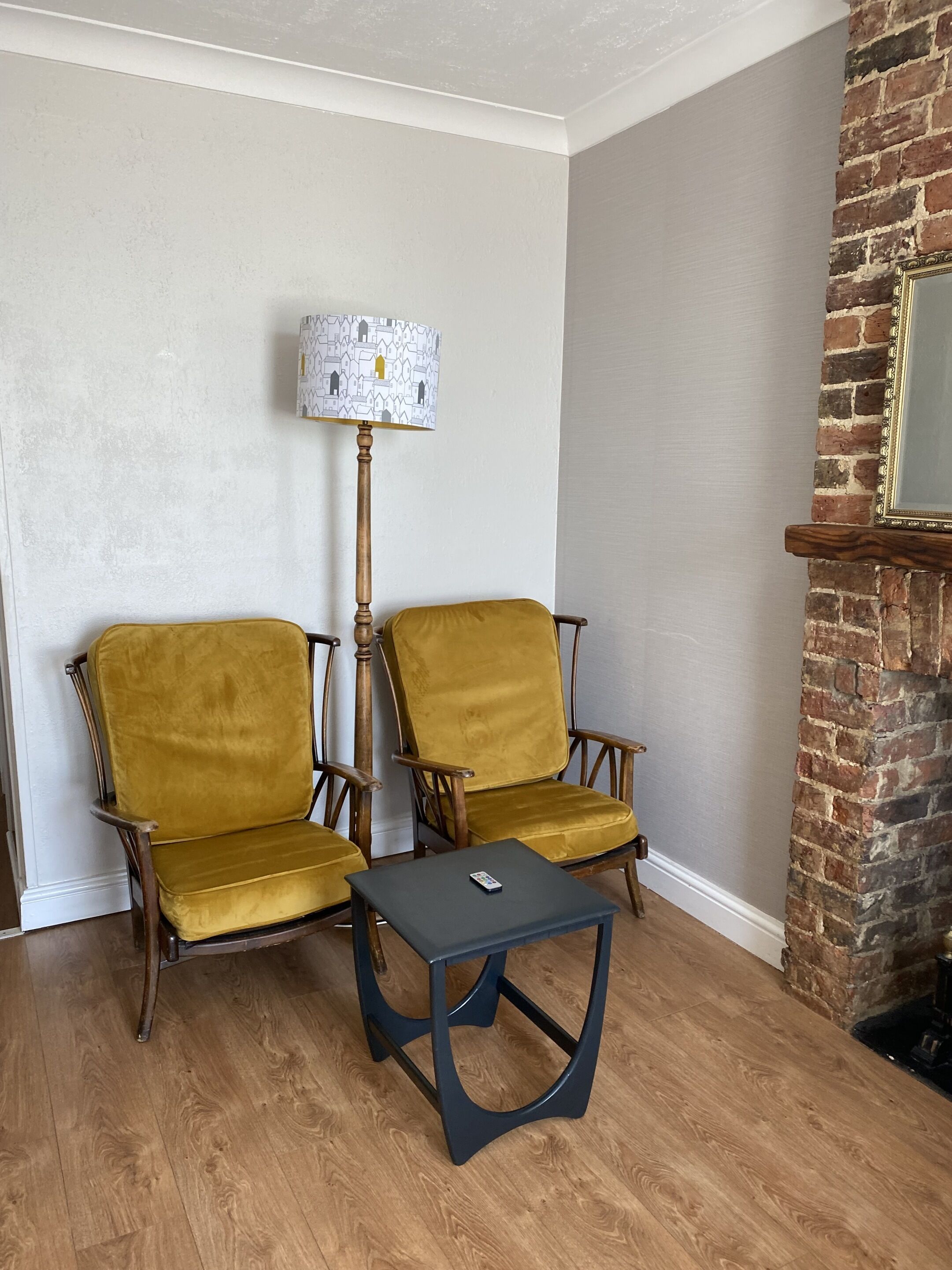A room with two yellow armchairs, a small table, and a floor lamp.