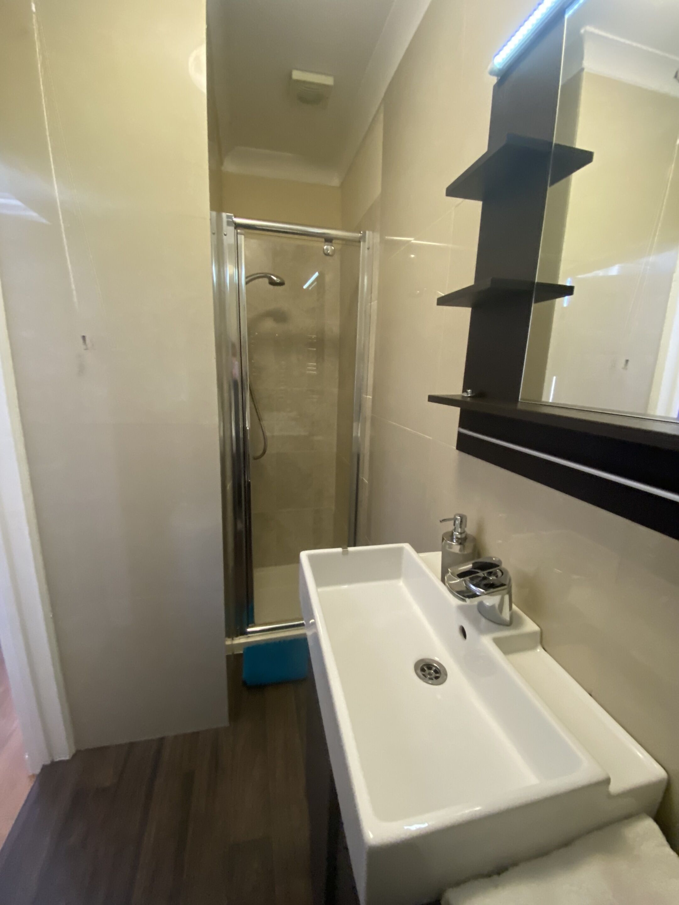 A bathroom with a white sink, a mirror, and a shower enclosure.