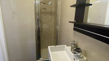 A bathroom with a white sink, a mirror, and a shower enclosure.