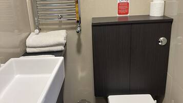 Un baño con un lavamanos blanco, un inodoro y un mueble de madera oscura.